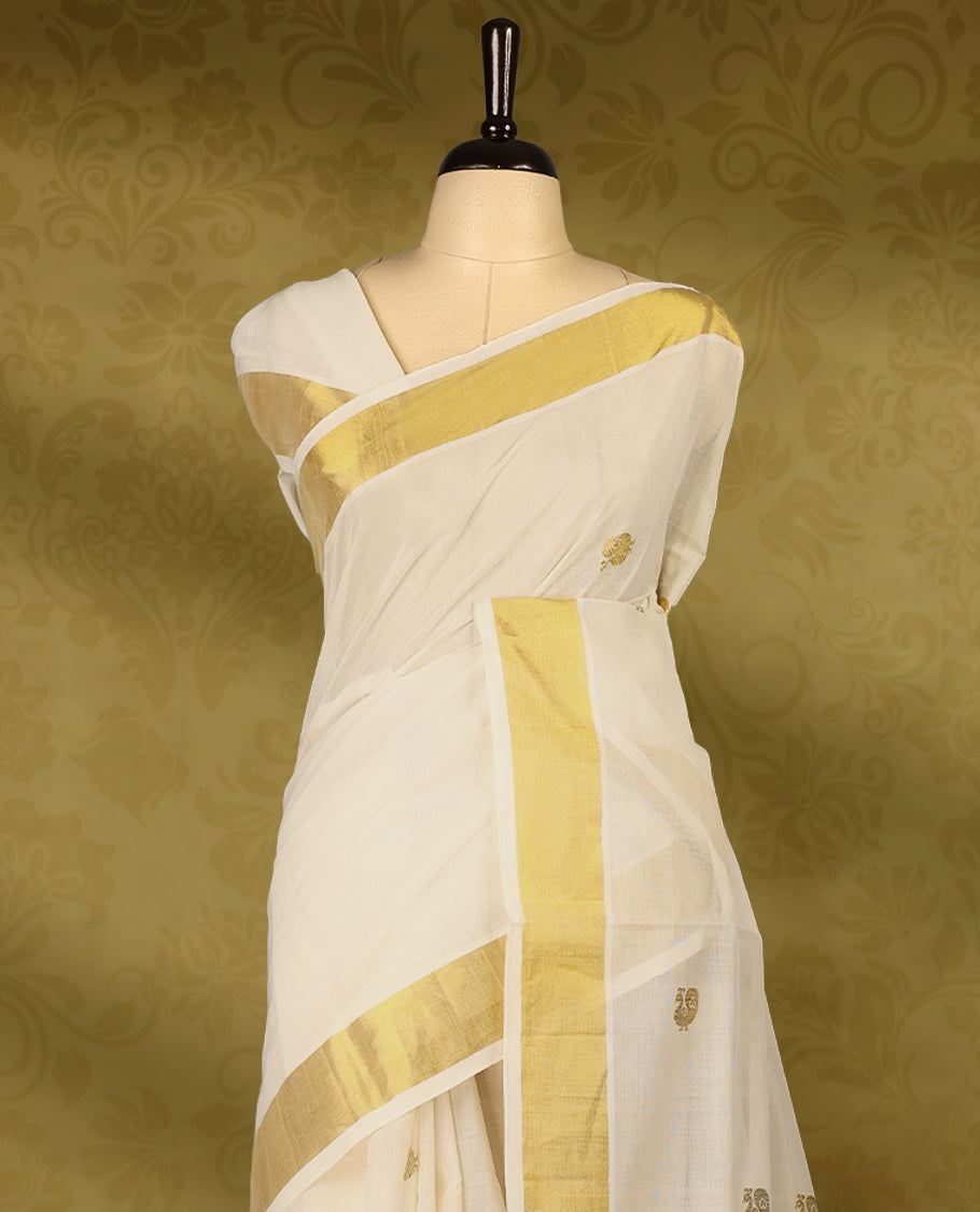 Off white colour pure handloom cotton kerala saree with small gold woven motifs on the body, golden zari border, pallu adorned with gold zari small peacock motifs, with matching blouse