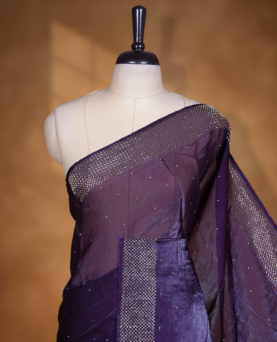Dark purple colour chiffon designer saree, featuring dainty scattered stones on the body, enriched with dense stone work and a heavy metallic stone border and pallu, paired with a matching blouse.