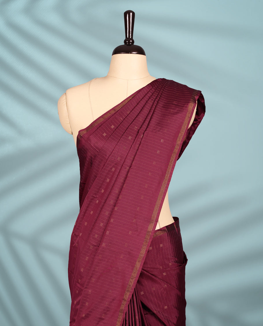 Maroon Red colour semi silk saree features a subtle checked body design with small woven motifs, a simple gold zari border, and comes with a matching blouse.