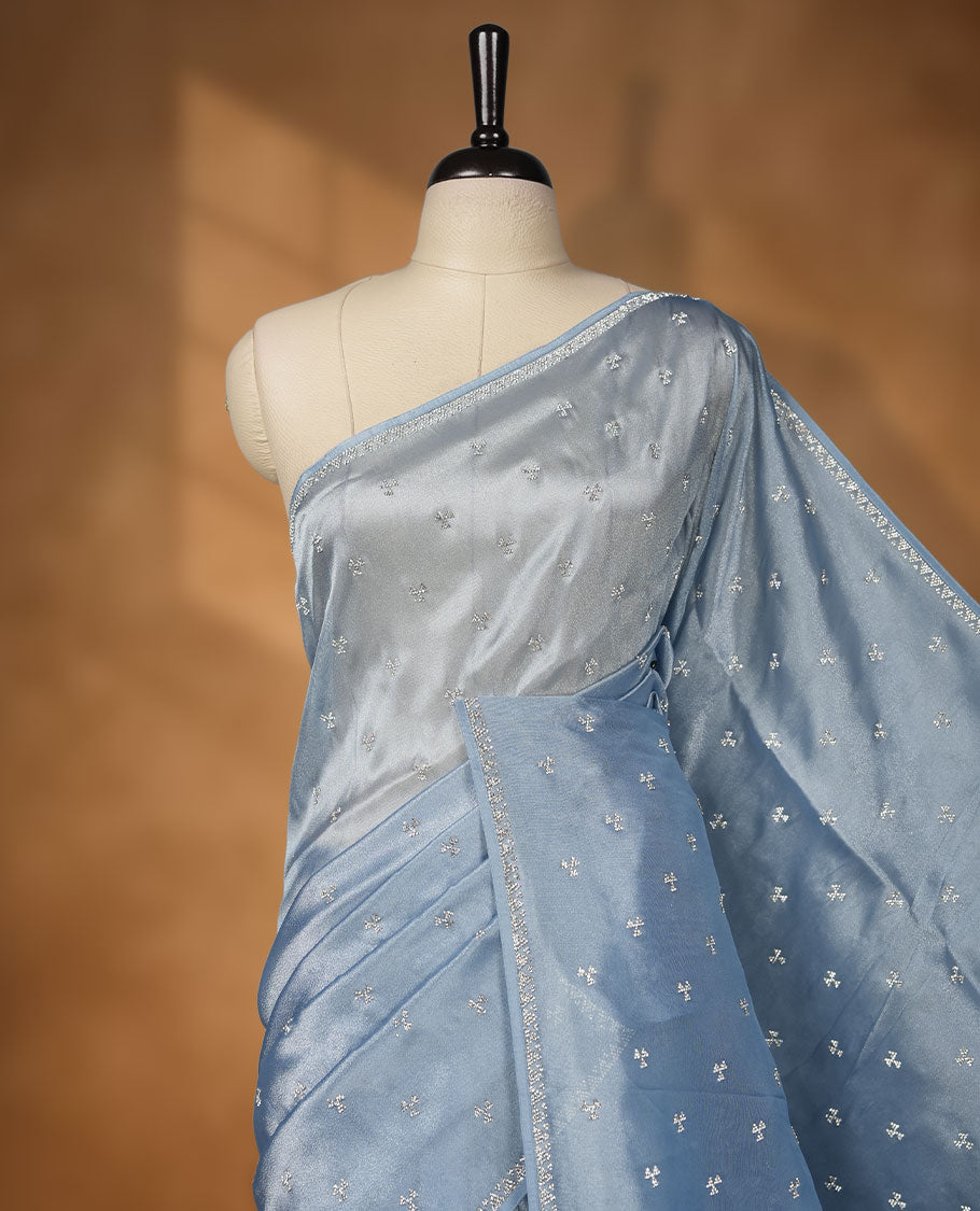 Pastel Blue colour net shimmer fancy saree adorned with scattered white stone buttas all over the body, paired with a delicate stone worked border and matching blouse featuring floral vine stone embroidery