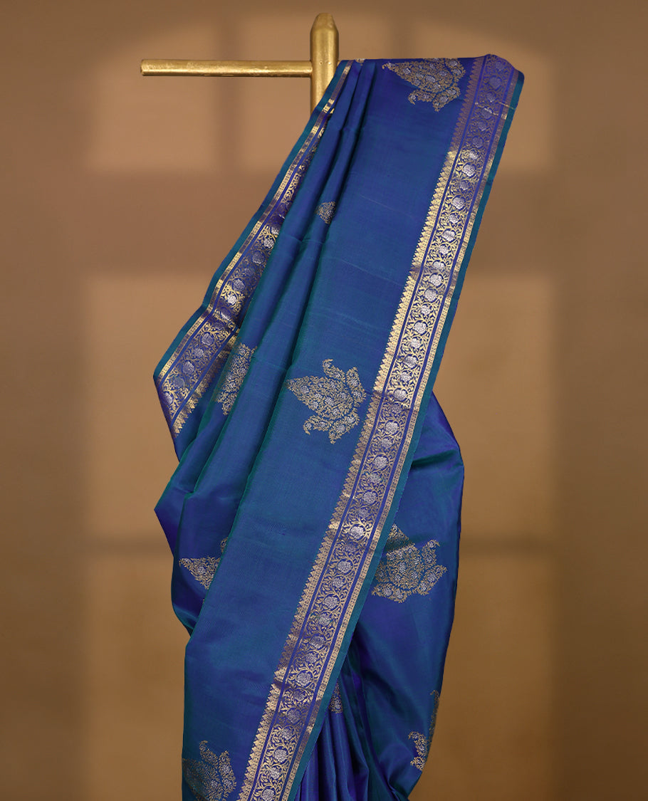 Double-shade peacock-coloured traditional Kancheepuram silk saree adorned with antique floral motifs on the body, featuring a traditional border with floral kodi designs, and paired with a matching blouse