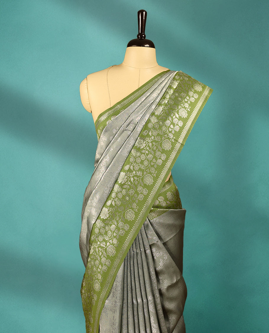 Light Pista coloured semi silk saree featuring a Silver coloured floral jaal design on the body, paired with a Green coloured border and matching blouse.