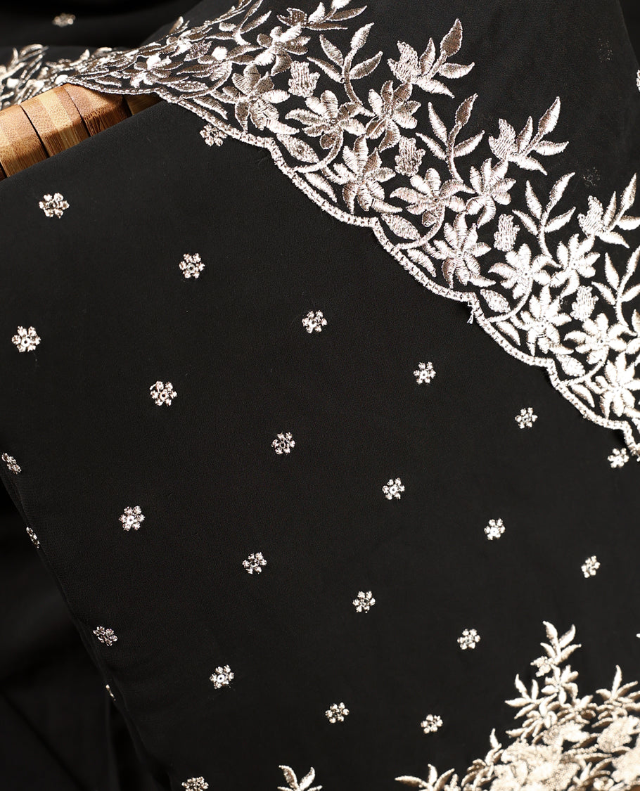 Black colour churidhar material beautifully designed with golden floral embroidery, thread highlights, paired with a plain matching bottom and an elegant embroidered dupatta.