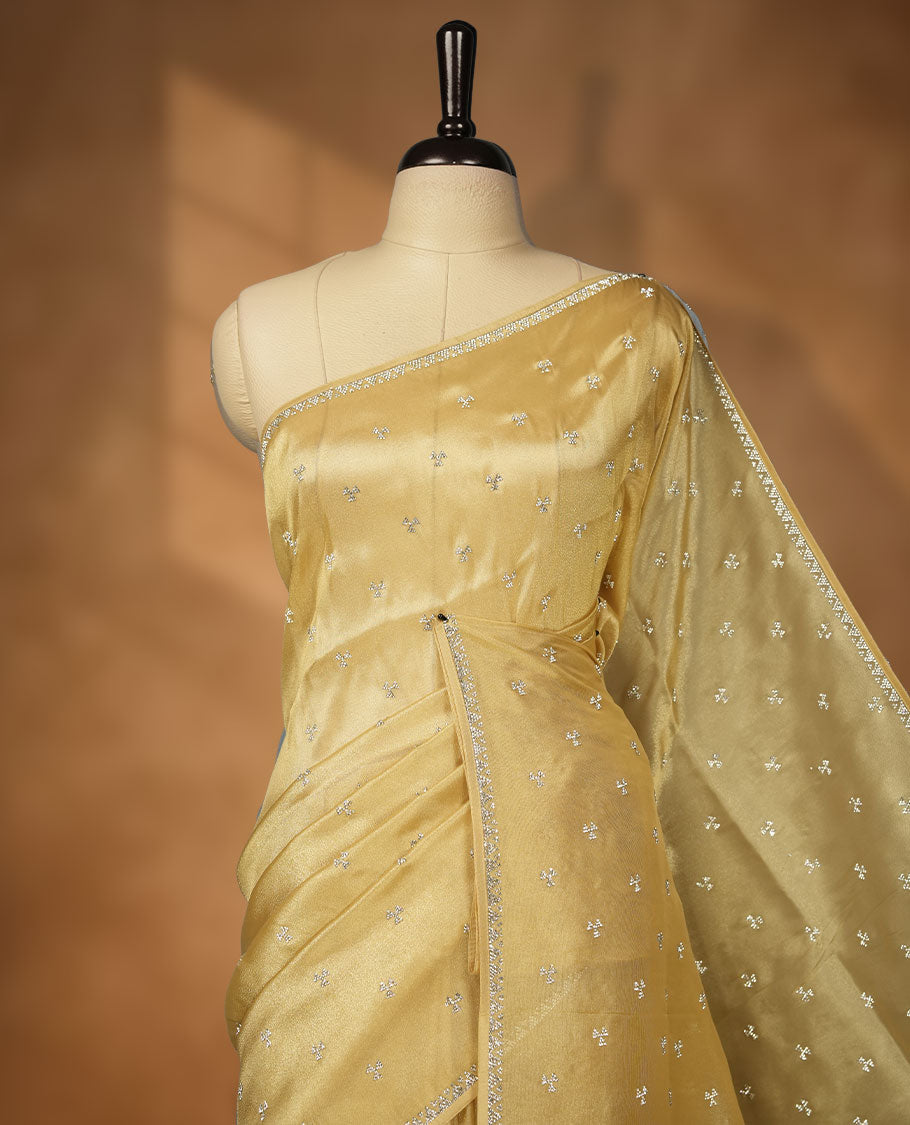 Golden Beige colour net shimmer fancy saree adorned with scattered white stone buttas all over the body, paired with a delicate stone worked border and matching blouse featuring floral vine stone embroidery