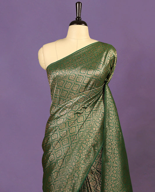 Green colour semi Banaras Katan saree featuring an antique Gold zari jacquard body, complemented by a self colour traditional border with a floral kodi design, paired with a matching blouse