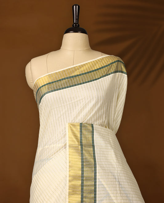 Elegant off white colour checked cotton Kerala saree with golden and green zari border, finished with tasselled pallu & Comes with a matching blouse, perfect for festive and traditional occasions.