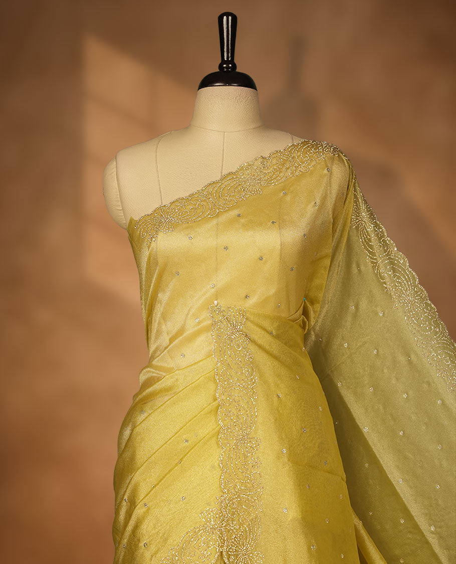 Golden olive colour net shimmer fancy saree adorned with white stone buttas, paired with a delicate stone worked border and matching blouse.