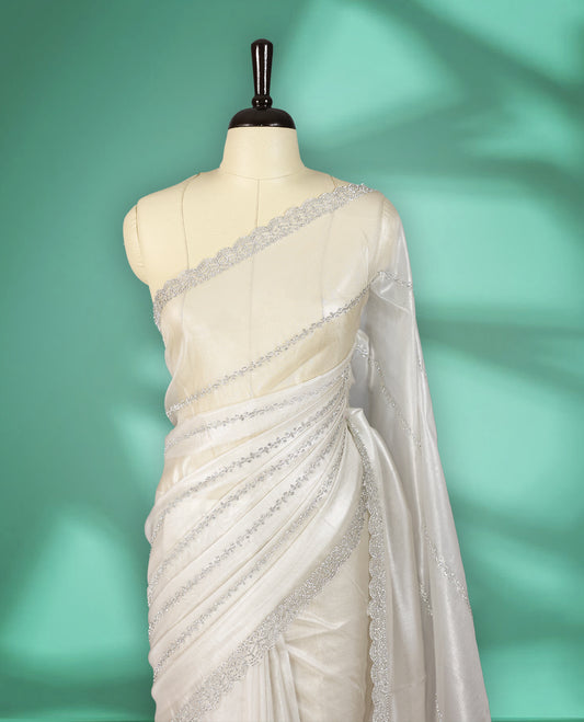 Off white colour net shimmer fancy saree adorned with subtle horizontal White stone patterns on the body, paired with a delicate stone worked border, with matching blouse