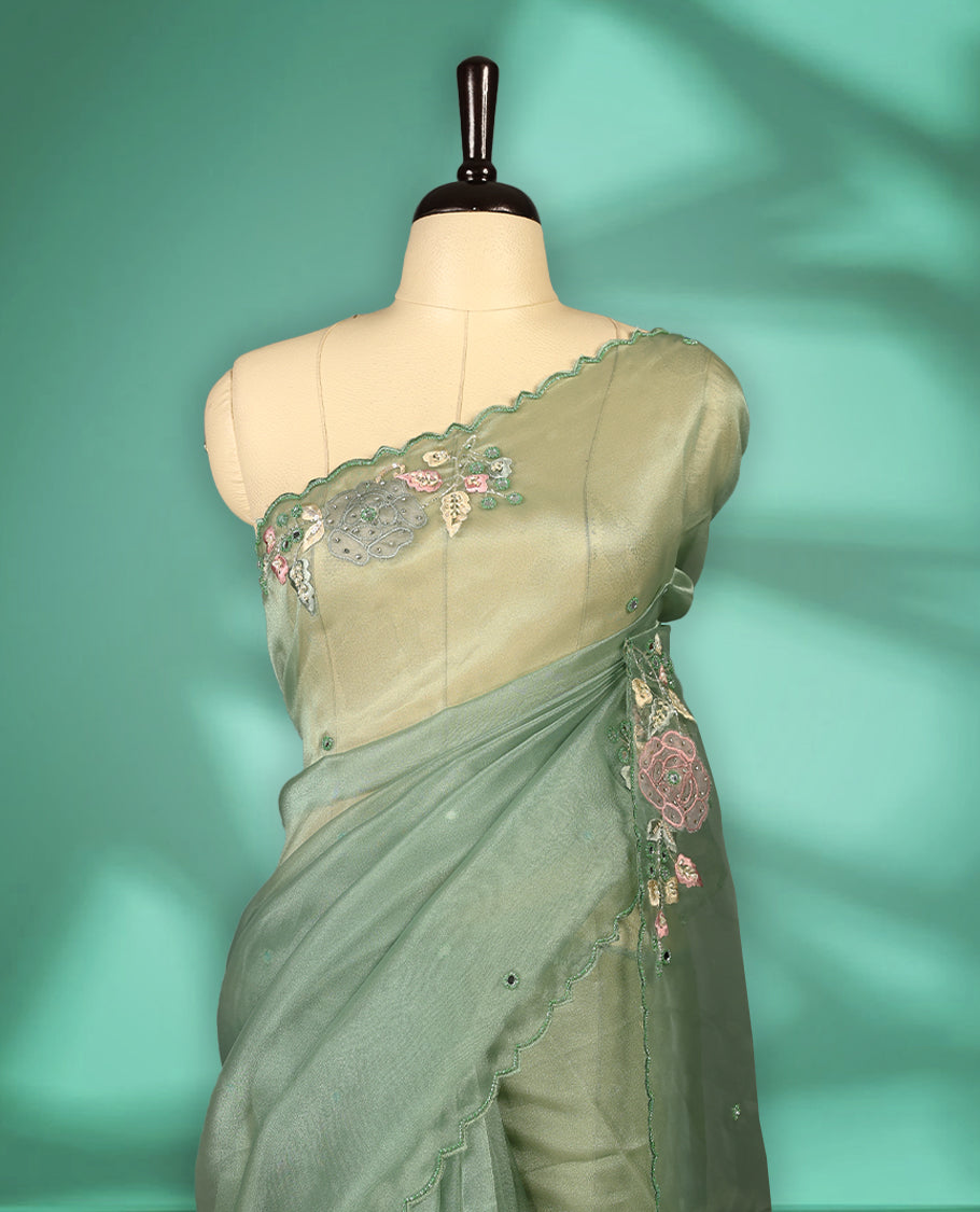 Pastel Green Colour organza saree featuring delicate floral embroidery with applique, bead, mirror, and thread detailing on the body and scalloped border, lending a soft feminine charm, paired with a matching blouse.