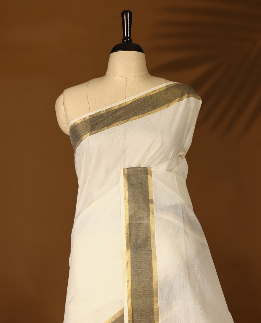 Elegant off white colour cotton Kerala saree featuring Plain body, Muted Black & golden zari kasavu border offering a classic and graceful look, paired with a matching blouse.