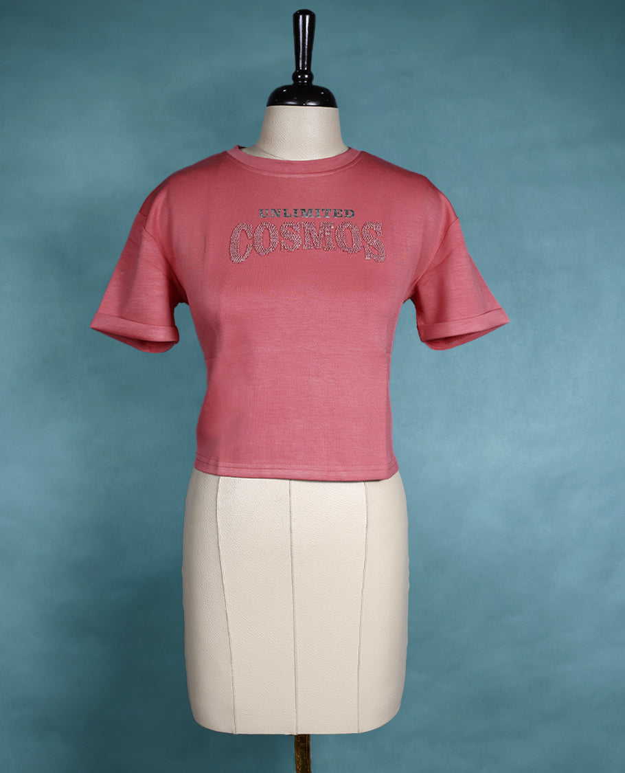 Rose pink cropped T shirt with short sleeves and rolled cuffs, featuring a subtle shimmer design on the front.