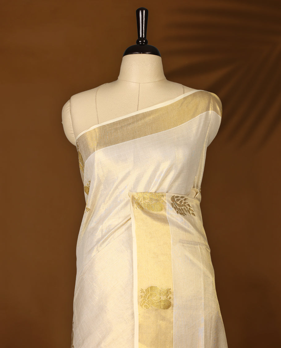 Elegant Light Gold colour Tissue Kerala saree featuring gold zari Leaf motifs on body, traditional golden zari kasavu border with peacock motifs & Rich Pallu paired with a matching blouse.