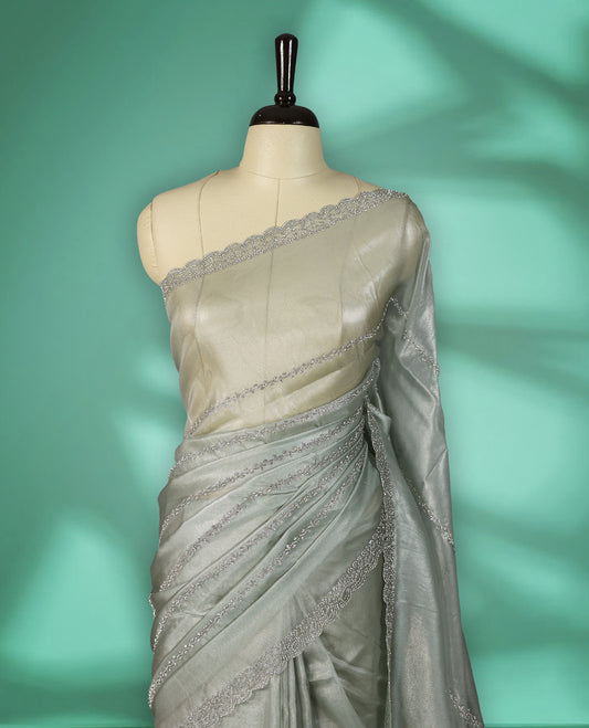 Light Pastel Green colour net shimmer fancy saree adorned with subtle horizontal White stone patterns on the body, paired with a delicate stone worked border, with matching blouse
