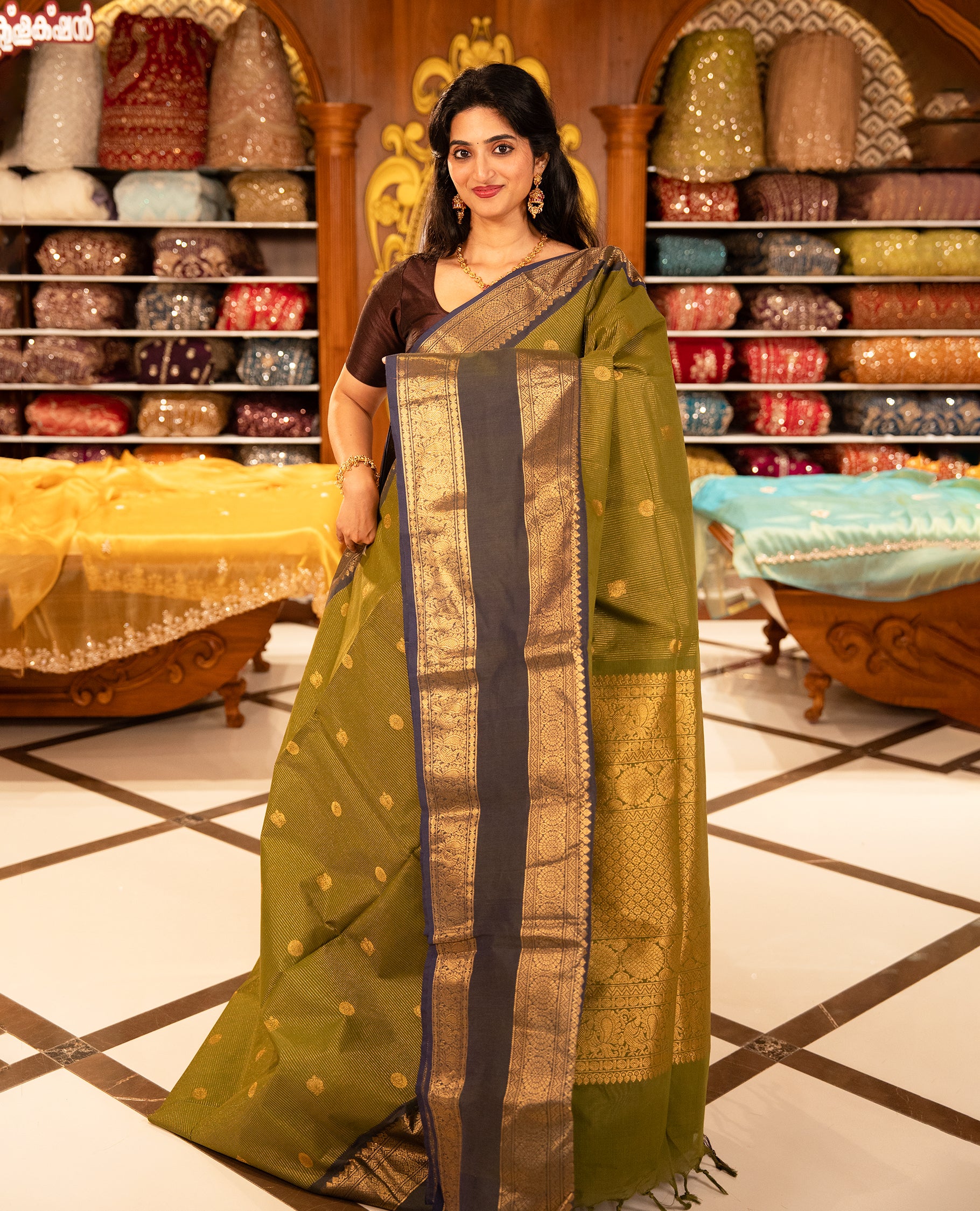 Olive with Blue colour Chettinad cotton saree featuring Gold zari strips with peacock motifs on body, complemented by contrast colour border with zari design & grand pallu, comes with matching blouse piece.