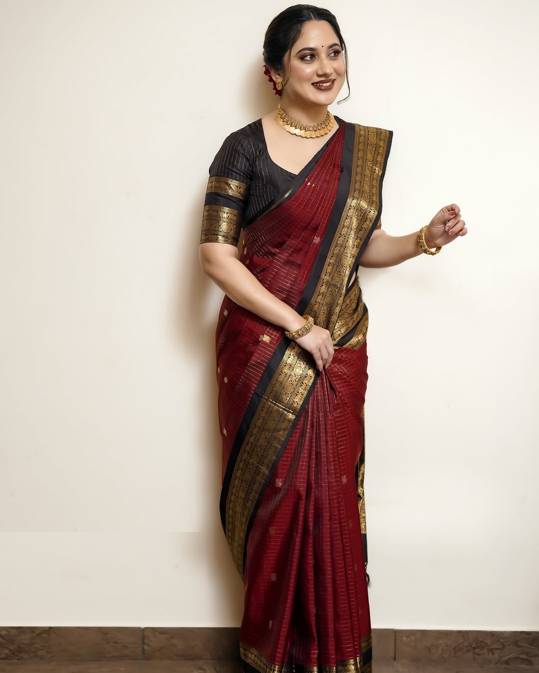 Elegant black and maroon pure Kancheepuram silk saree featuring gold zari elephant & floral brocade border rich maroon body with gold checkered patterns and Gold & Silver colour Peacock Motifs, traditional pallu paired with matching blouse