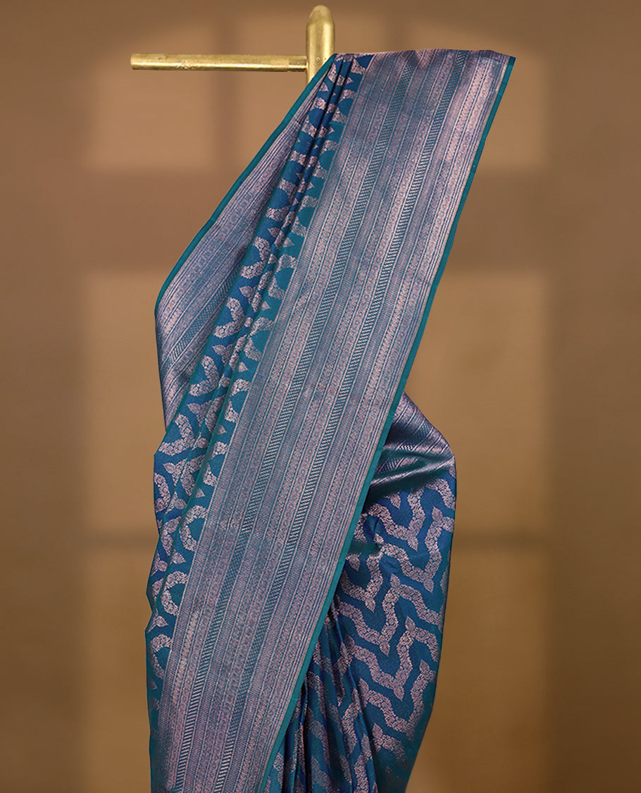 Peacock Blue Colour Manthrakodi saree featuring an antique zari Banarasi design on the body, complemented by a self coloured traditional border and a matching self coloured blouse.