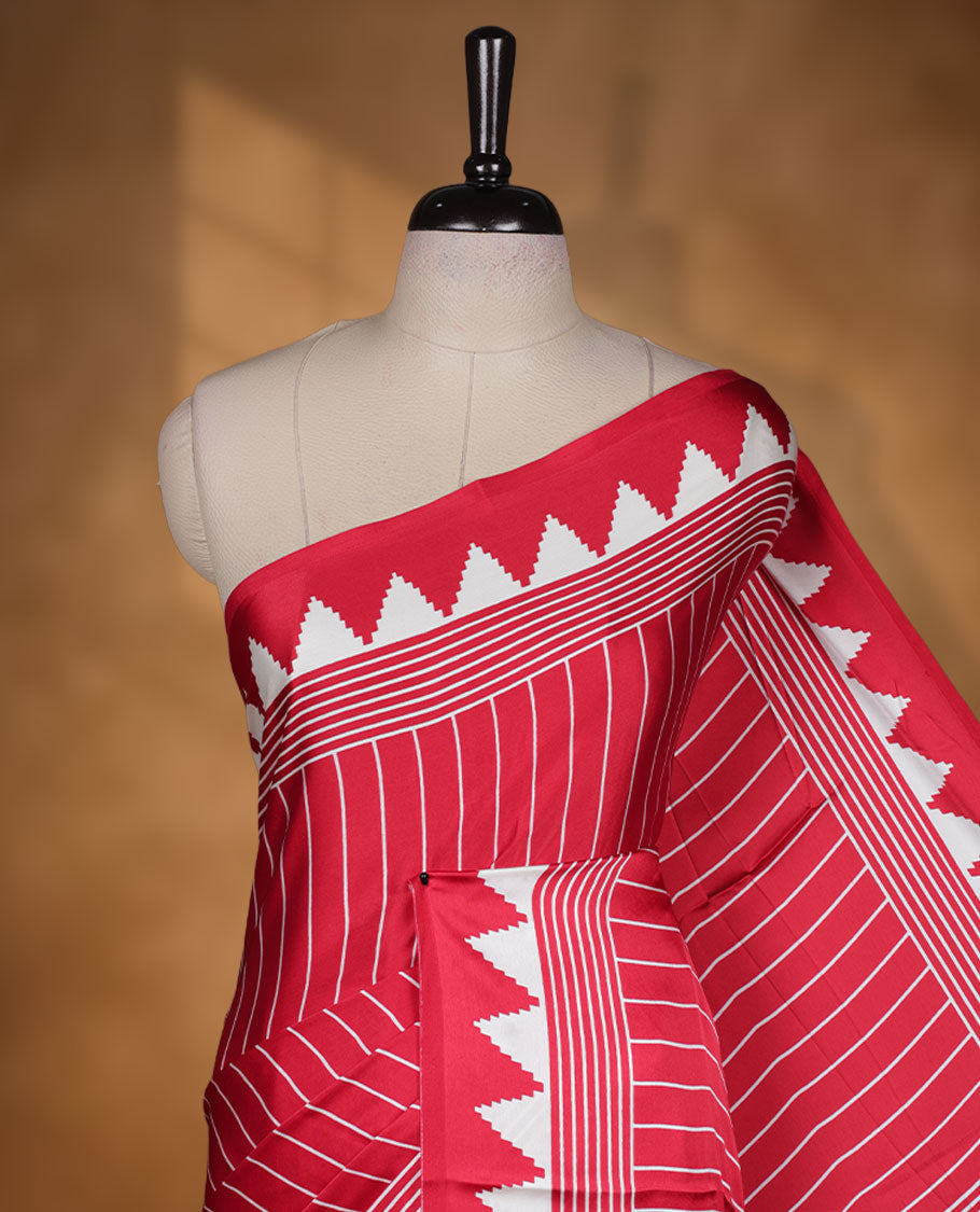 Red colour semi modal saree featuring white colour geometric borders and fine stripe detailing, finished with an oversized circular motif on the pallu, paired with a matching printed blouse.