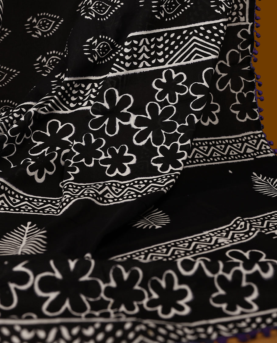 Black cotton saree features intricate white handblock prints, a beautifully detailed border with Violet piping and Self Coloured Blouse