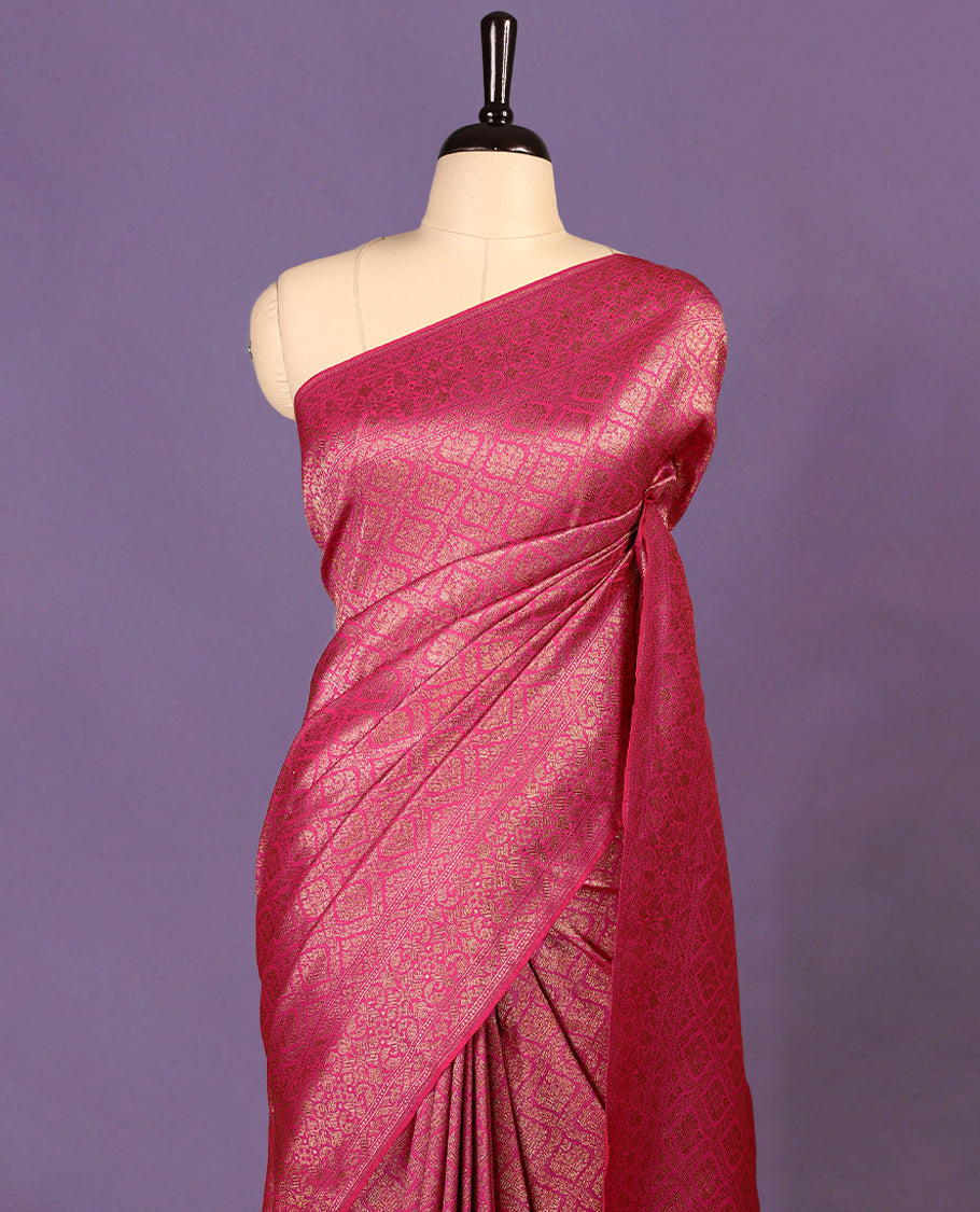 Magenta colour semi Banaras Katan saree featuring an antique Gold zari jacquard body, complemented by a self colour traditional border with a floral kodi design, paired with a matching blouse