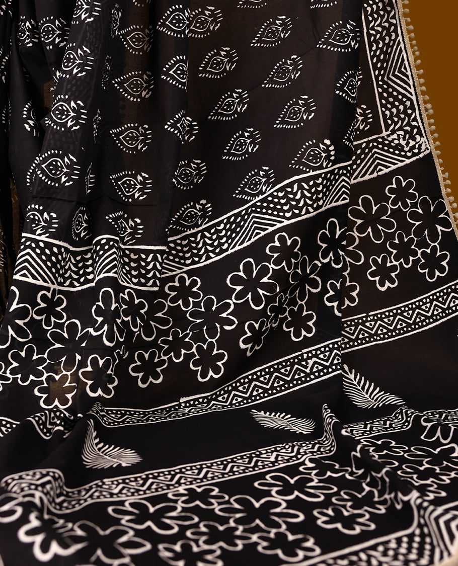 Black cotton saree features intricate white handblock prints, a beautifully detailed border with Beige piping and Self Coloured Blouse