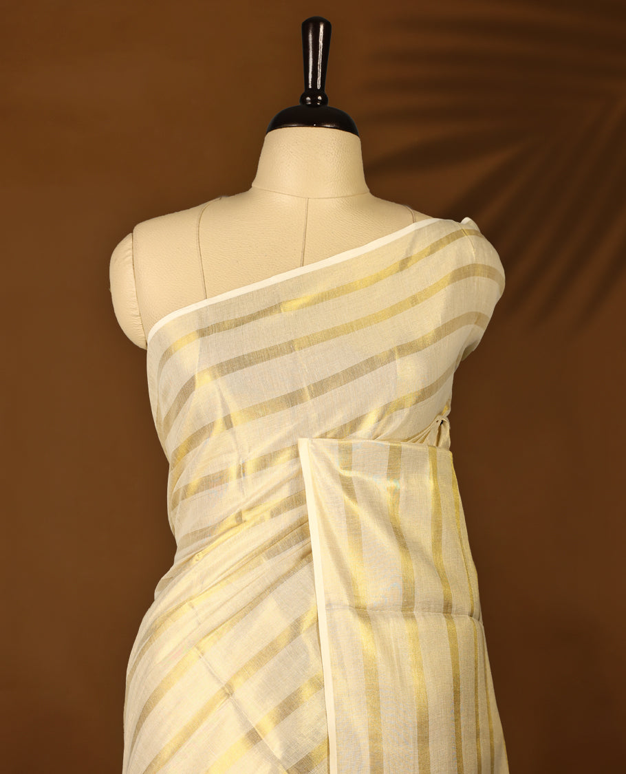 Light Gold colour Tissue Kerala saree featuring Gold zari Striped body, with Green colour tassels with a matching blouse perfect for festive occasions.