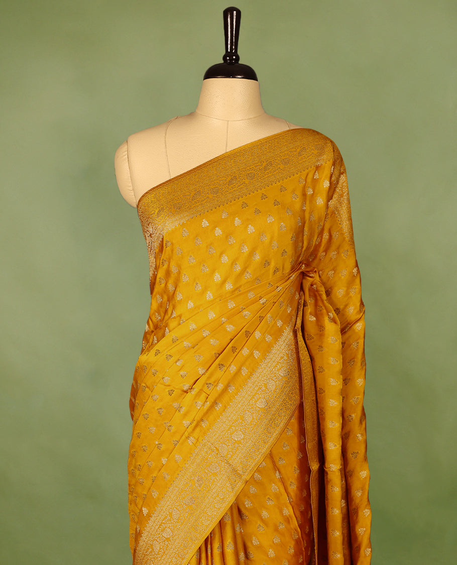 Mustard Gold semi-Banaras satin crepe saree featuring traditional closely woven buttas on the body, complemented by an antique-style border and a matching self-coloured blouse.