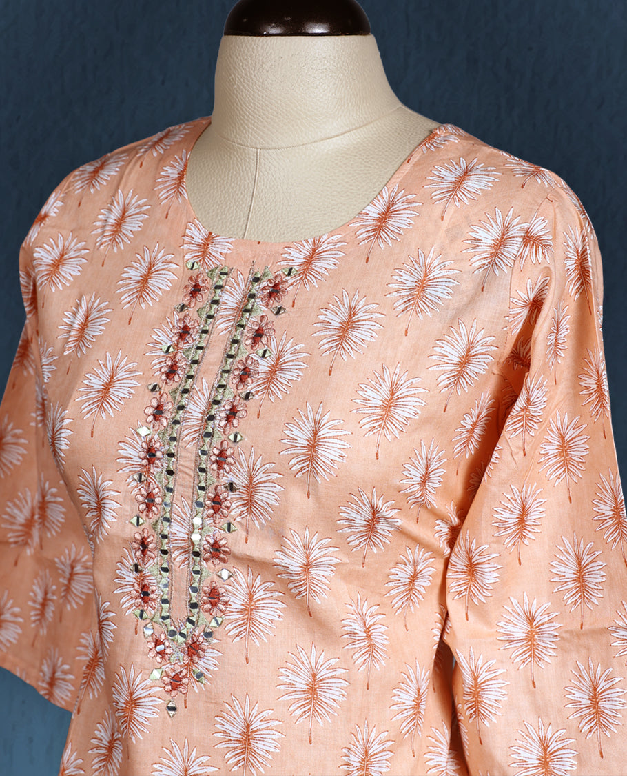 Peach colour kurti with all over white floral prints, featuring a round neckline adorned with vertical thread and mirror embroidery, and three quarter sleeves