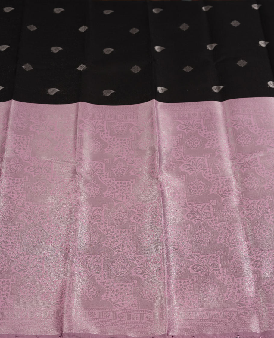 Black colour semi silk saree adorned with subtle silver zari motifs on the body, complemented by a pastel pink pallu intricately woven with rich floral patterns border and pallu, and paired with a matching blouse