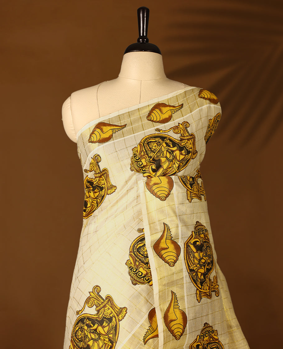 Light Gold colour Tissue Kerala saree featuring Lord Krishna and peacock motifs on the body, golden zari checks, and a beautifully woven border with shell Printed motifs, paired with a matching blouse perfect for festive occasions.