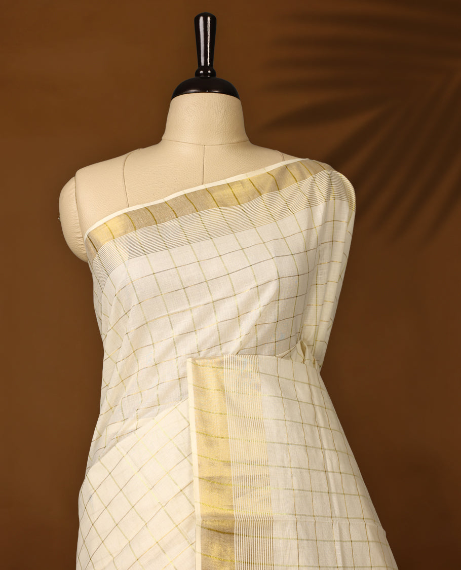 Elegant off white colour cotton Kerala saree with subtle golden and golden checked patterns and a broad golden zari border, Lightweight, breathable, and perfect for traditional events, Includes blouse piece.