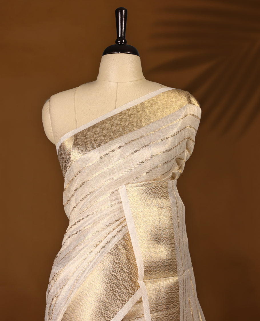 White & gold colour Organza Kerala saree featuring a smooth body with Gold zari Stripes, highlighted by a sleek golden zari border, Bold pallu Paired with a matching blouse.