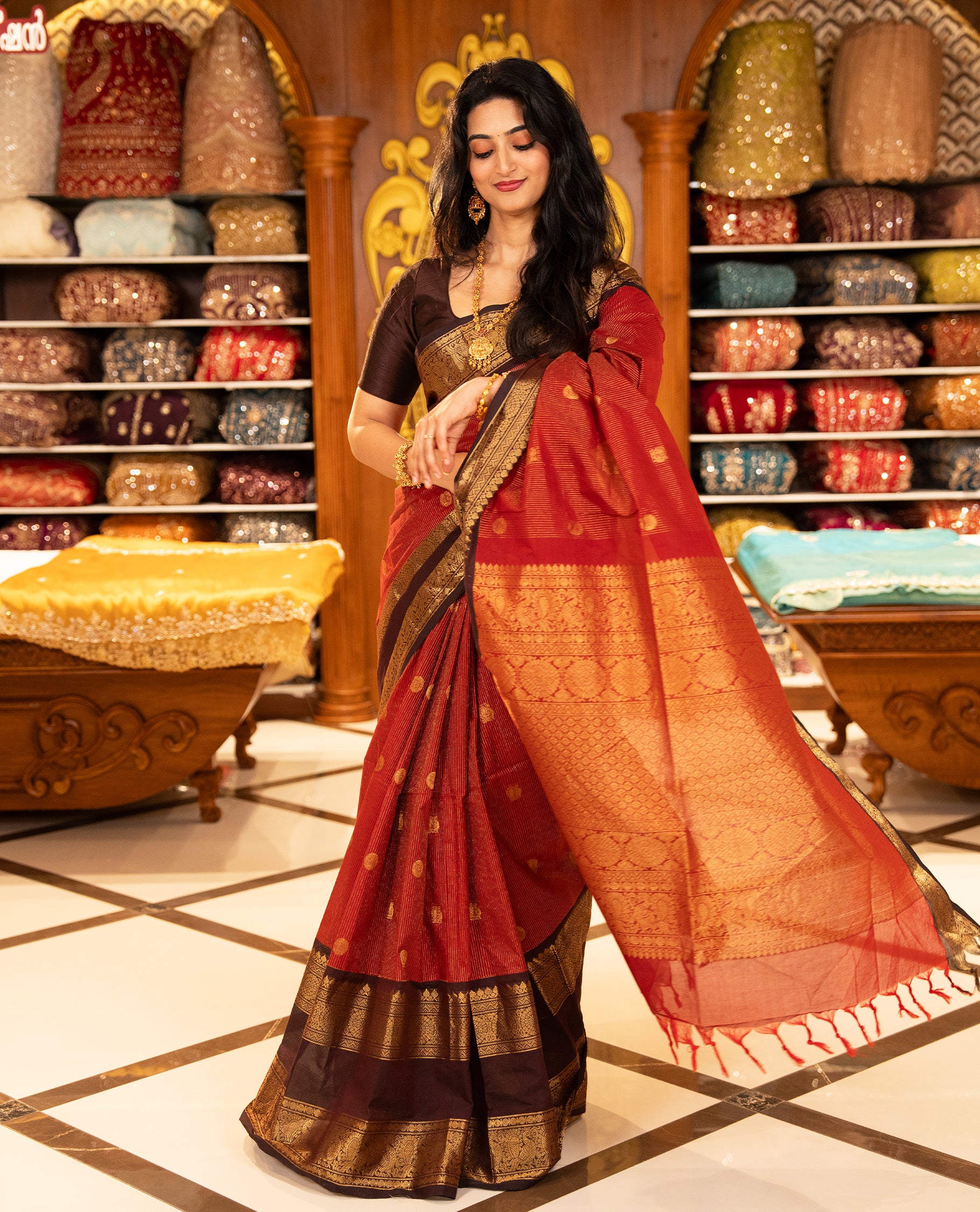 Maroon with Brown Chettinad cotton saree featuring Gold zari strips with peacock motifs on body, complemented by contrast colour border with zari design & grand pallu, comes with matching blouse piece.