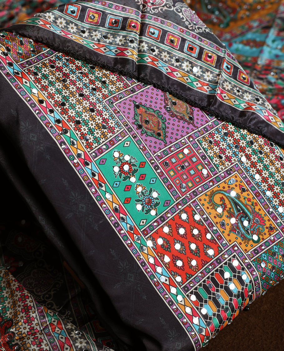 Striking black churidhar material featuring vibrant multicolour geometric and paisley prints highlighted with delicate mirror work, paired with a plain matching bottom and bold printed dupatta, ideal for festive occasions.