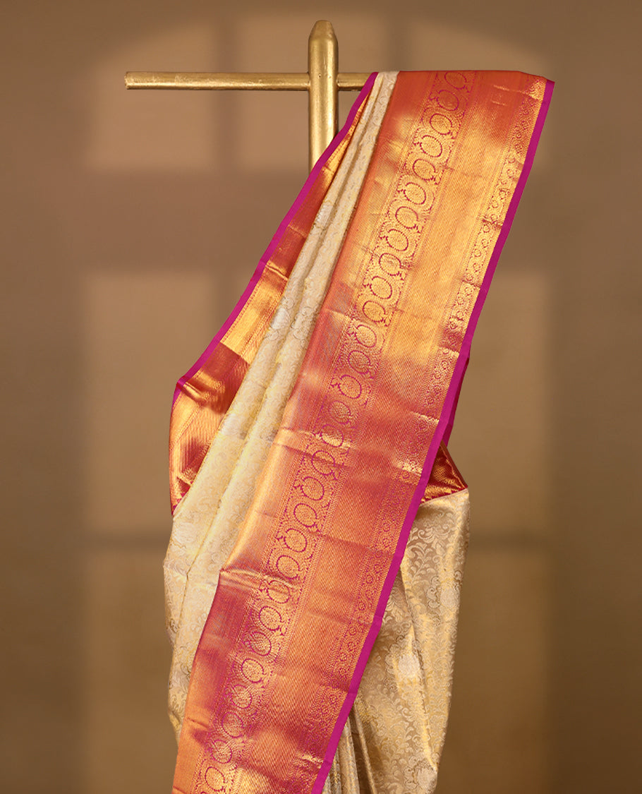 Golden Colour Kancheepuram tissue silk saree adorned with intricate silver and gold zari floral jaal work on the body, enhanced by a contrasting traditional floral kodi design border, paired with a matching blouse.