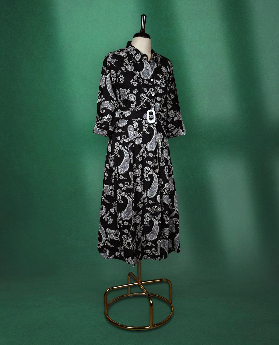 Black shirt style kurti dress featuring elegant white paisley prints, designed with a collared neckline, front buttons, 3/4th sleeves, and a matching fabric belt to accentuate the waist perfect for a smart Indo western look.
