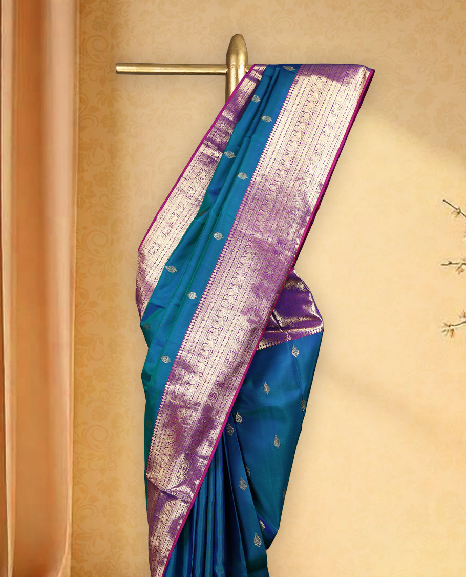 Peacock blue colour pure Kancheepuram saree with gold zari traditional paisley motifs on the body contrast traditional border with peacock, winged horse and chackram motifs grand pallu with diamond pattern paired with matching blouse