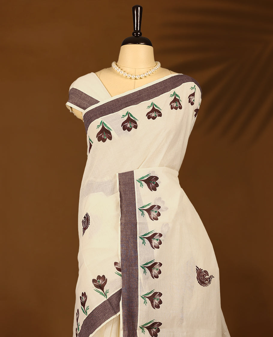 Kerala cotton saree features beautiful floral Prints in earthy tones, paired with a deep brown border with Matching Blouse.
