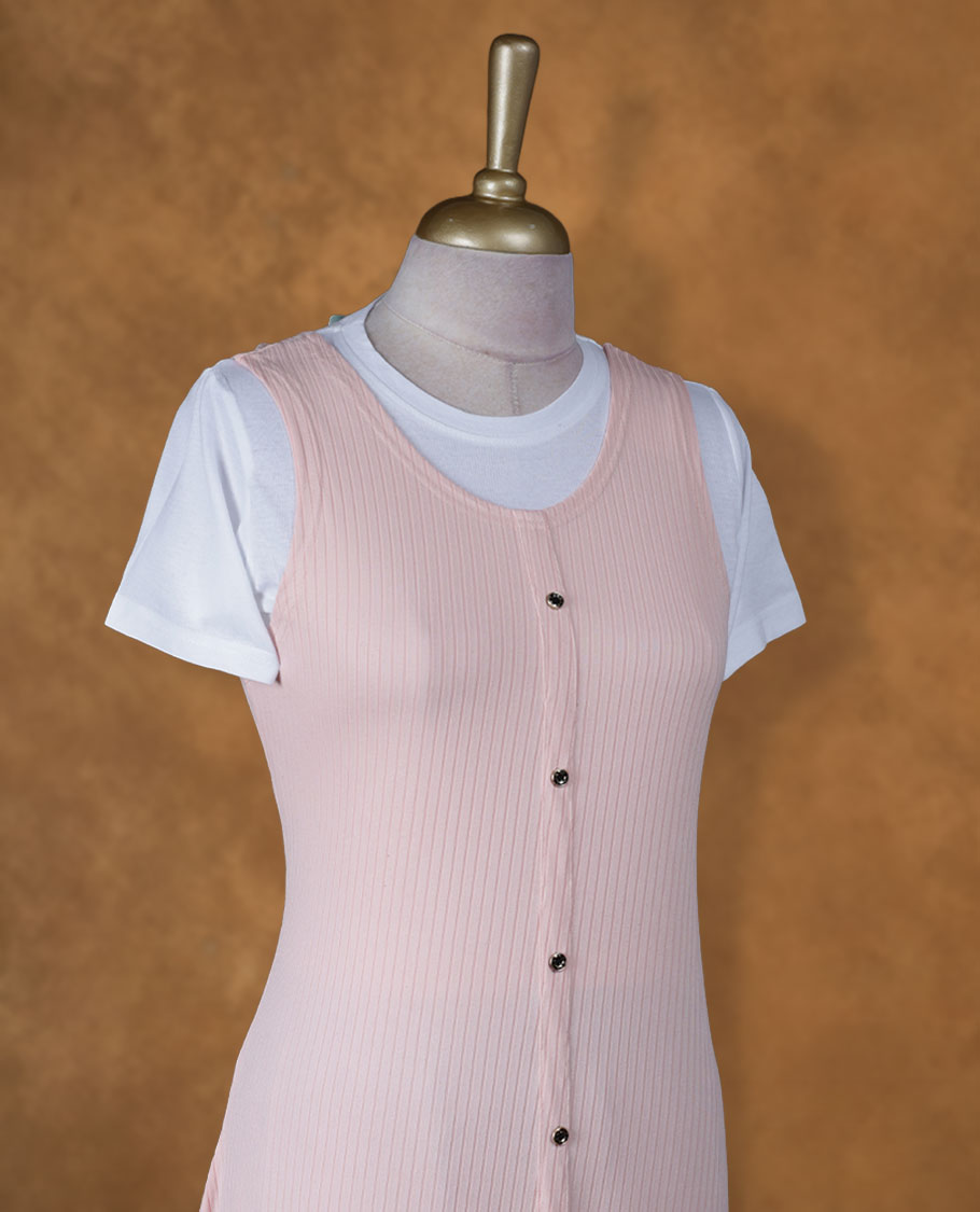 Blush pink sleeveless A-line midi dress with front button detailing, layered over a white crew-neck short-sleeve inner tee