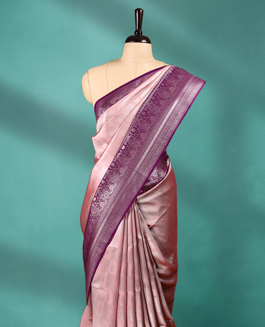 Pastel Peach coloured semi silk saree featuring a Silver coloured Zari design on the body, paired with a Grape coloured border and matching blouse.