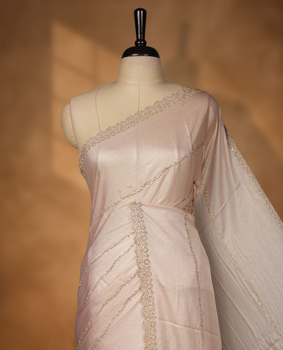 Pale pink colour net shimmer fancy saree adorned with scattered gold stone buttas all over the body, paired with a delicate stone worked border and matching blouse.