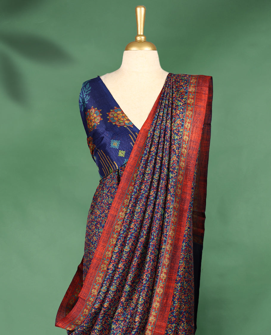 Navy blue colour Manipuri saree adorned with an all over floral pattern in multicolour hues, complemented by a rich rust-red border and matching blouse.