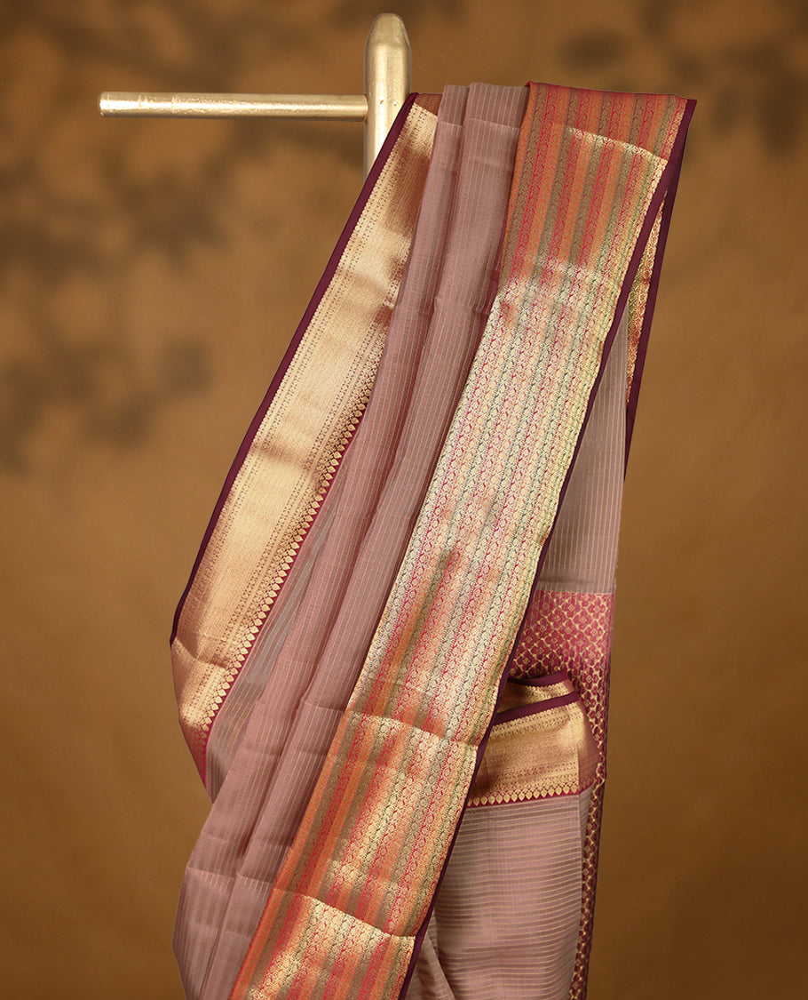 Warm brown Colour soft silk saree with subtle reddish undertones, adorned with golden vertical pinstripes, featuring a contrasting traditional border and paired with a matching blouse.
