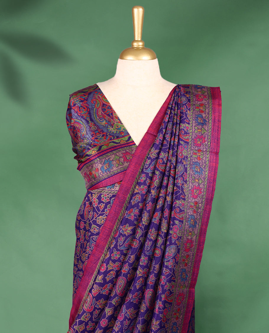 Purple Colour saree with multicolour floral and paisley motifs, detailed Contrast border, and a traditional design that comes with a matching blouse.