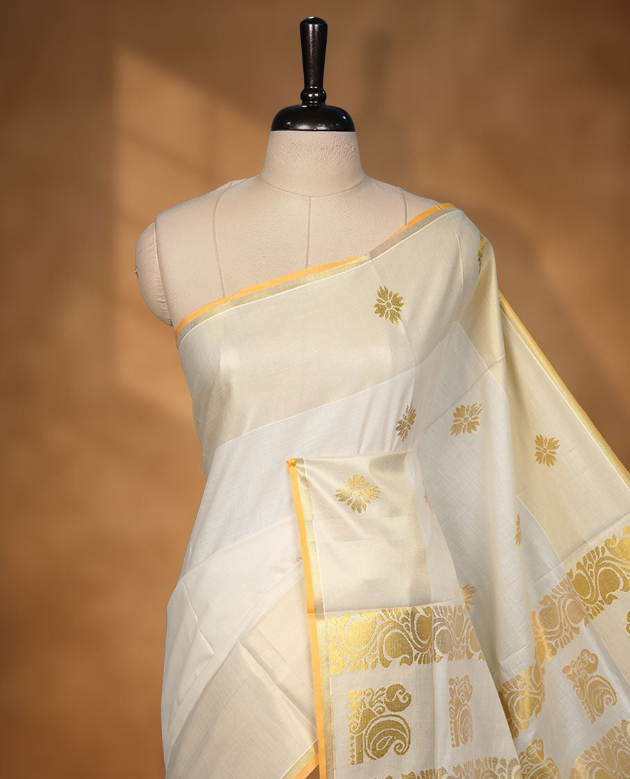 off-white cotton Kerala saree adorned with rich gold zari motifs across the pallu, finished with a classic kasavu border and subtle buttas on the body, paired with a matching blouse