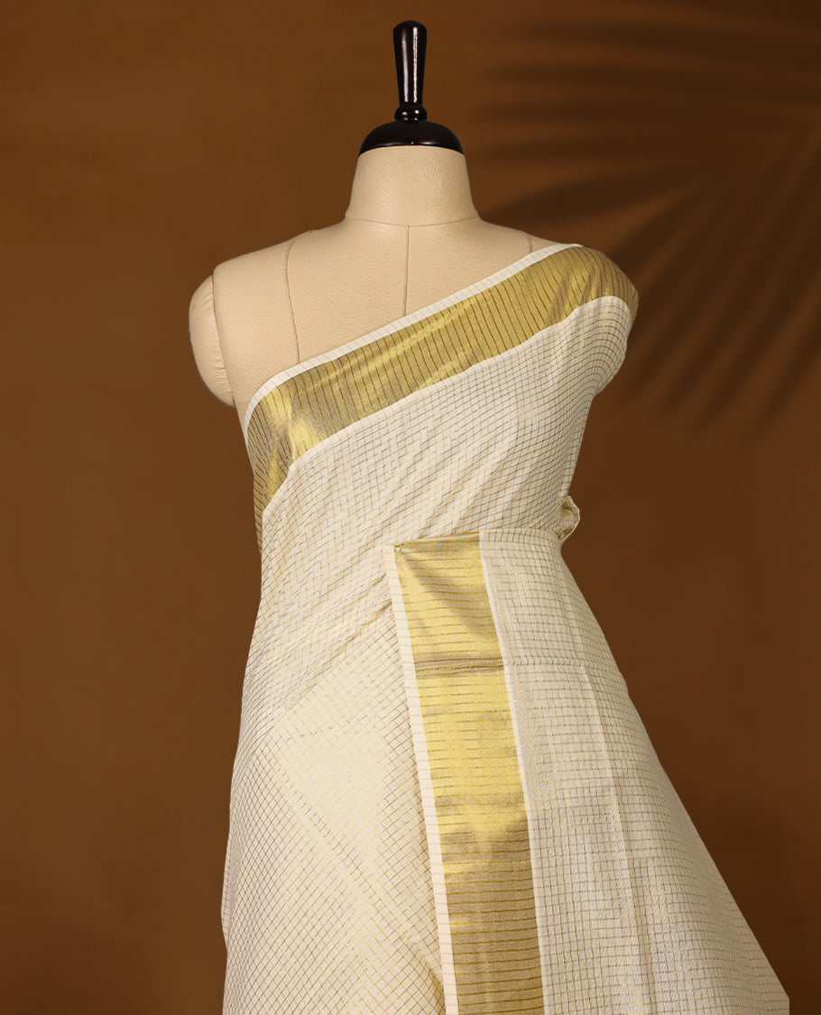 Elegant off white colour cotton Kerala saree featuring Tiny Checked body, gold zari traditional kasavu border offering a classic and graceful look, paired with a matching blouse.