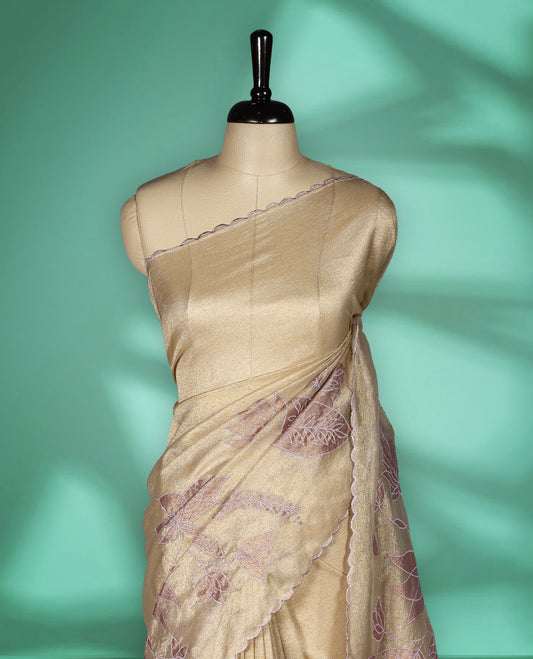 Champagne beige colour organza designer saree featuring subtle woven texture on the body, adorned with soft mauve floral embroidery along the border and pallu, finished with scalloped Thread edging paired with matching blouse.