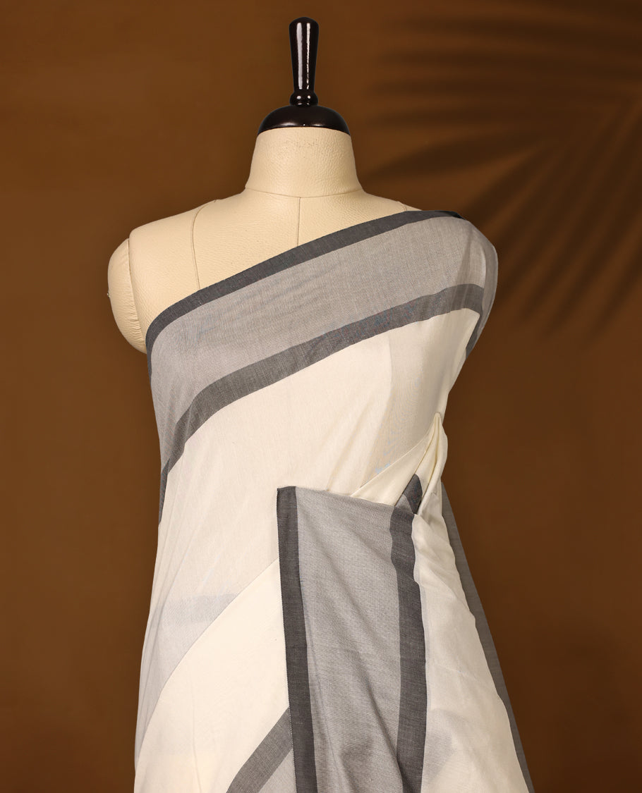 Elegant off white colour Kerala cotton saree with soft grey and charcoal borders, finished with tassel detailing,Lightweight and breathable, it comes with a matching blouse & perfect for everyday, festive, or office wear.