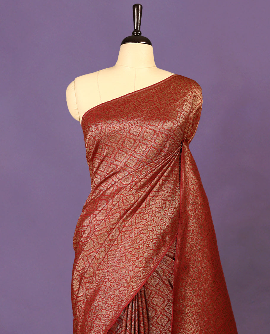 Maroon colour semi Banaras Katan saree featuring an antique Gold zari jacquard body, complemented by a self colour traditional border with a floral kodi design, paired with a matching blouse