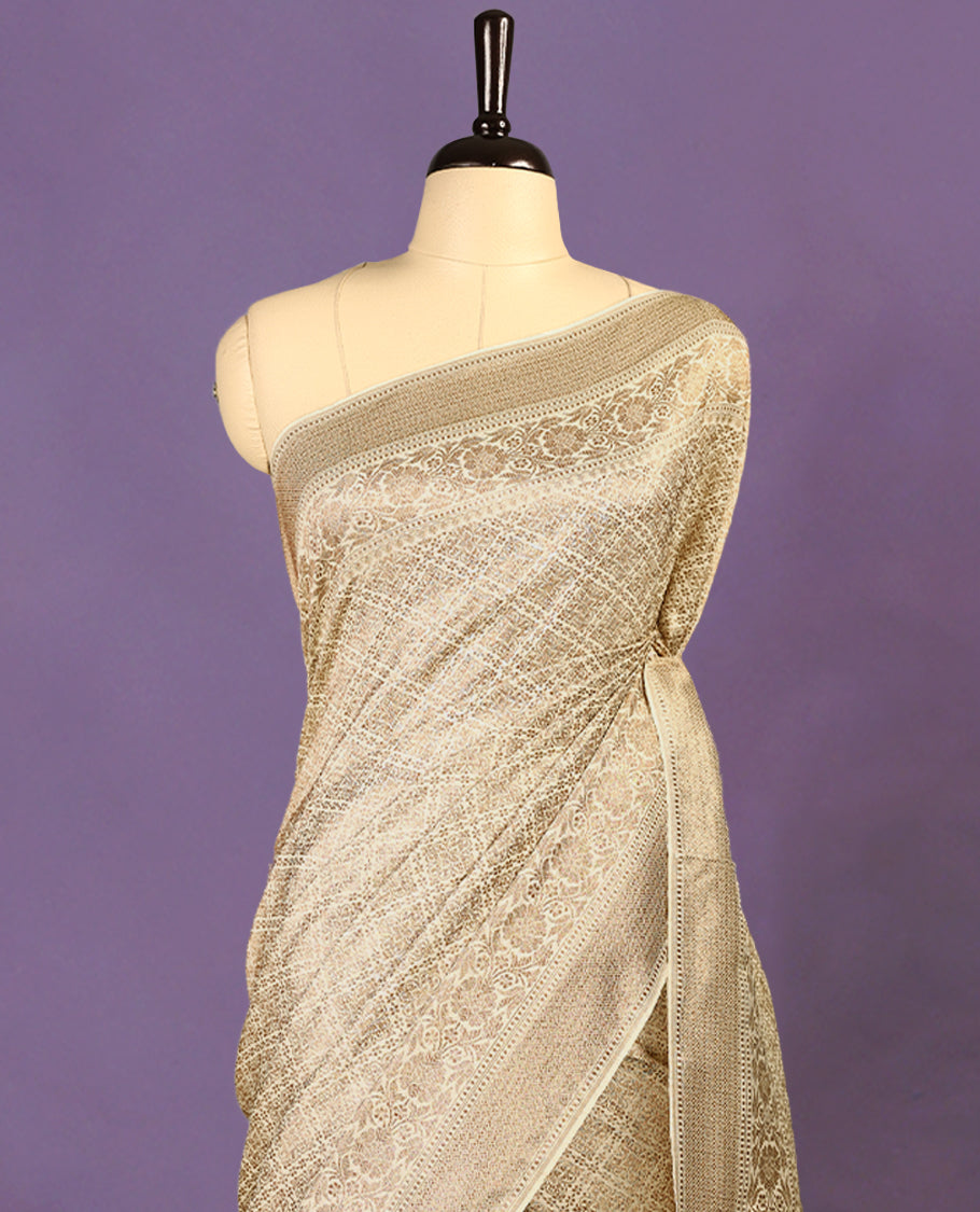 Off White colour semi Banaras Katan saree featuring an antique Gold zari jacquard body, complemented by a self colour traditional border with a floral kodi design, paired with a matching blouse