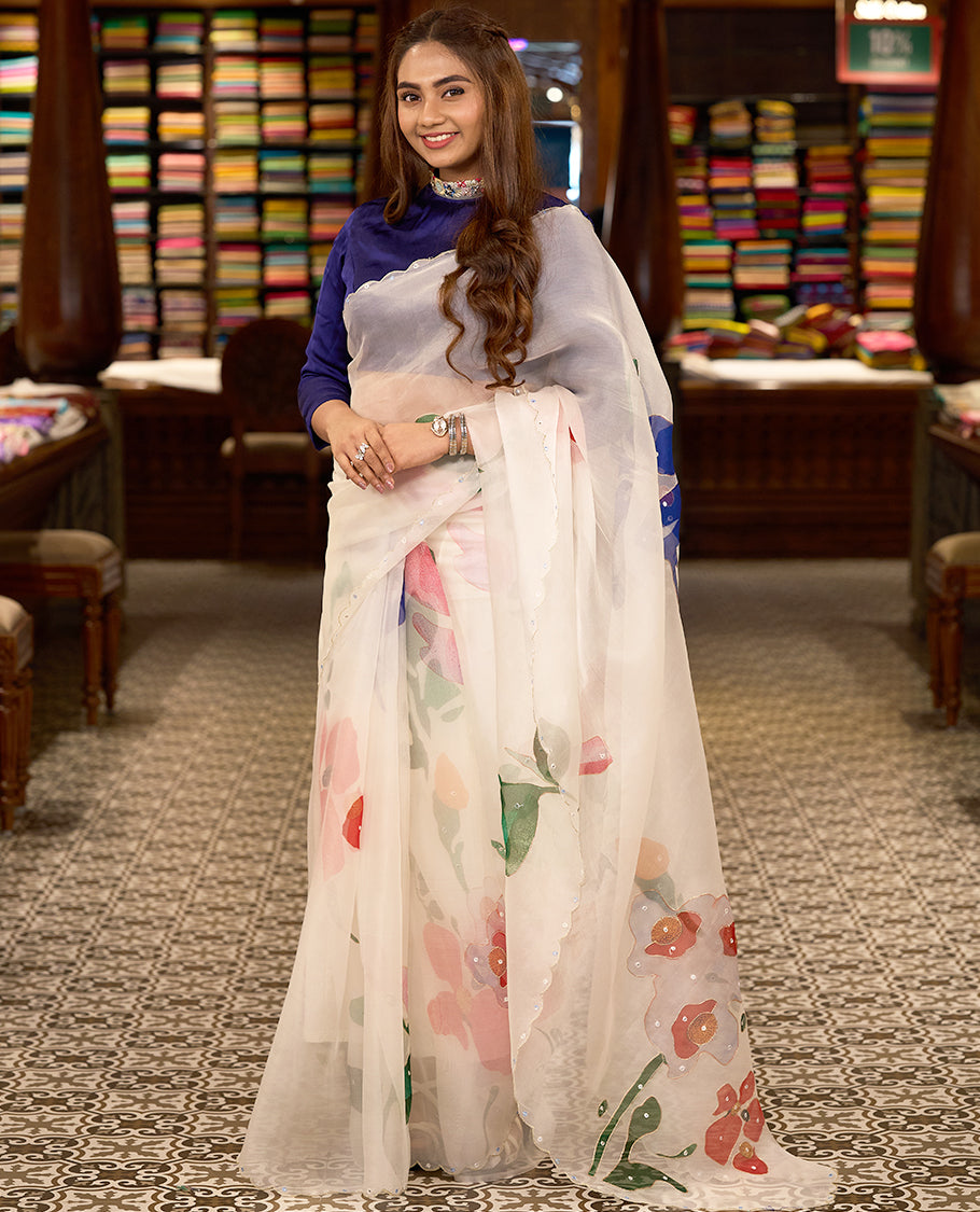 White colour pure organza silk saree featuring digitally printed fancy floral designs, adorned with delicate small mirror work, and finished with an elegant scalloped border, paired with a self colour crepe printed blouse